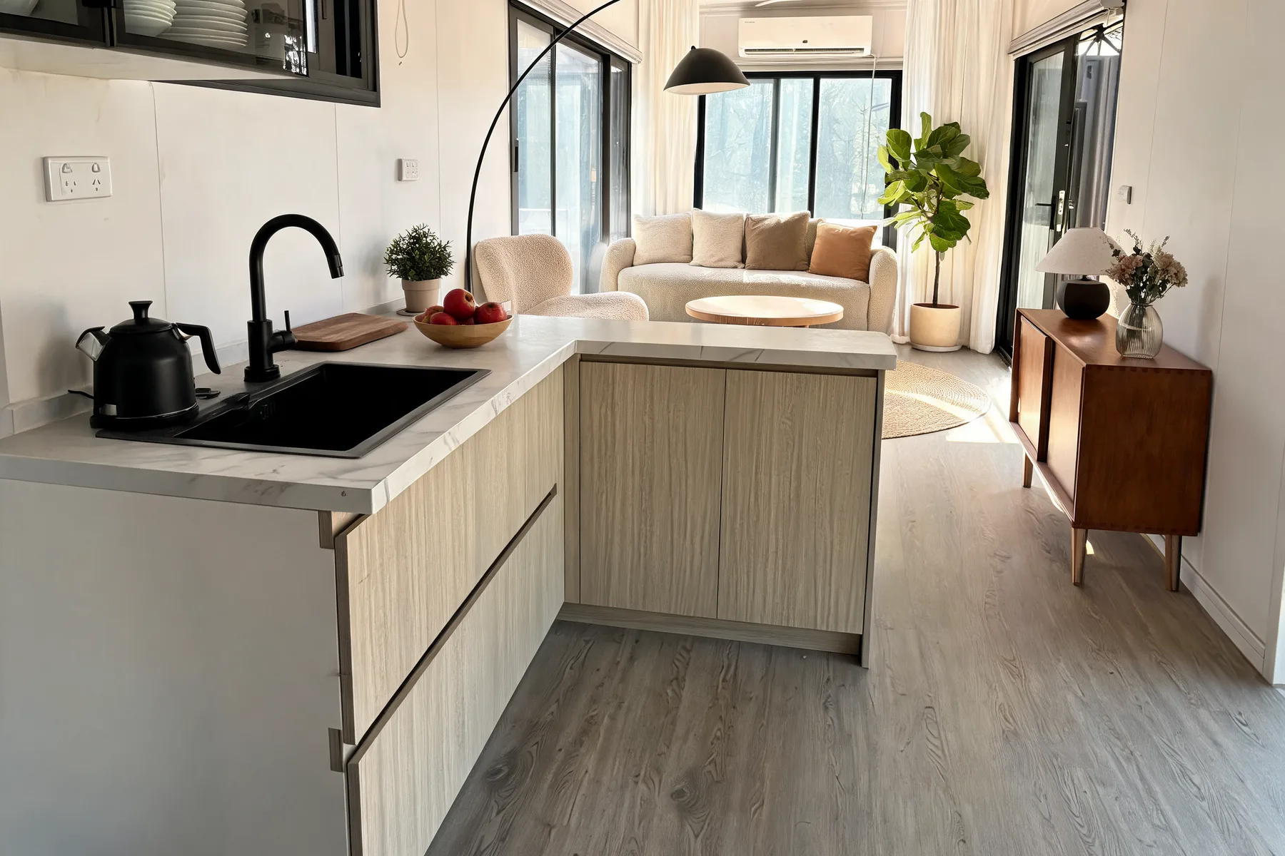 Finished kitchen with marble benchtop, black sink and tapware, opening onto the living area of a Lima modular home